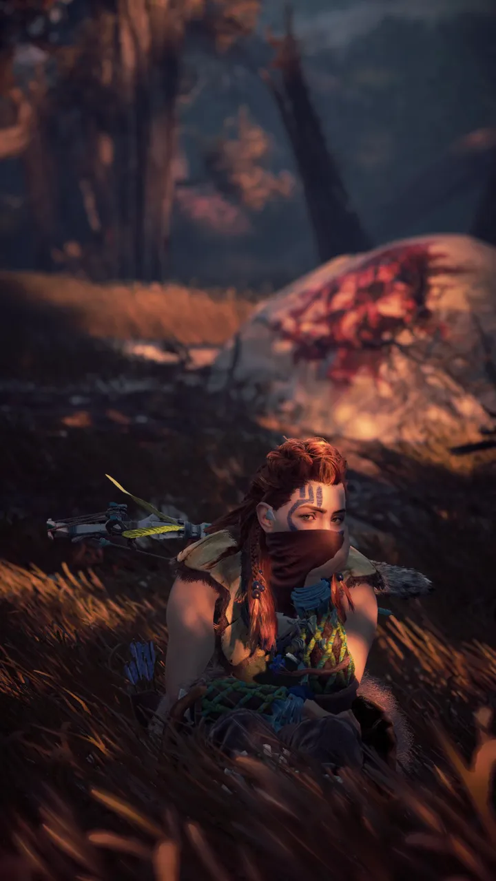 Aloy sitting in the shadow, her mouth covered by a bandana